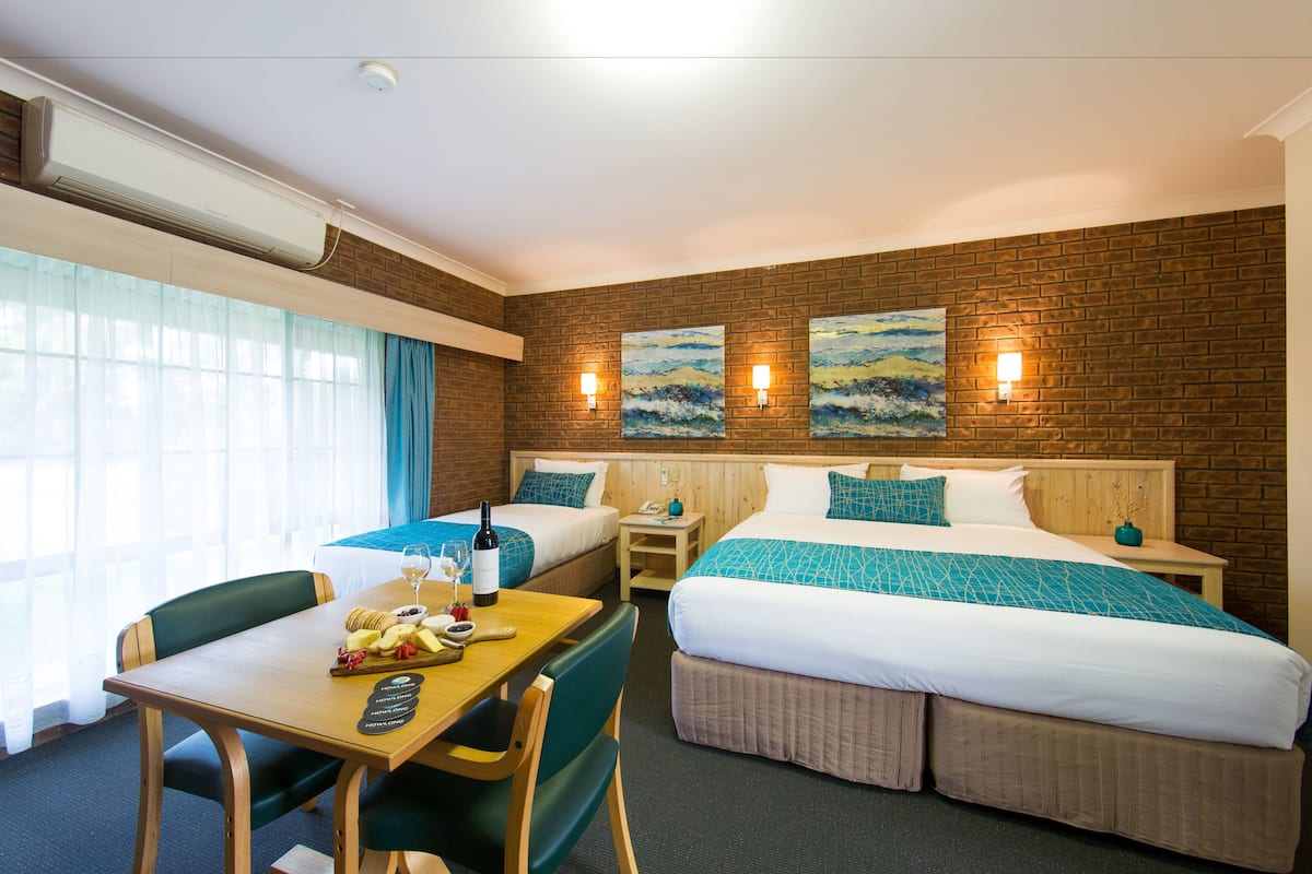 Ein Hotelzimmer mit zwei Betten, einem Esstisch und einer kleinen Küchenzeile.