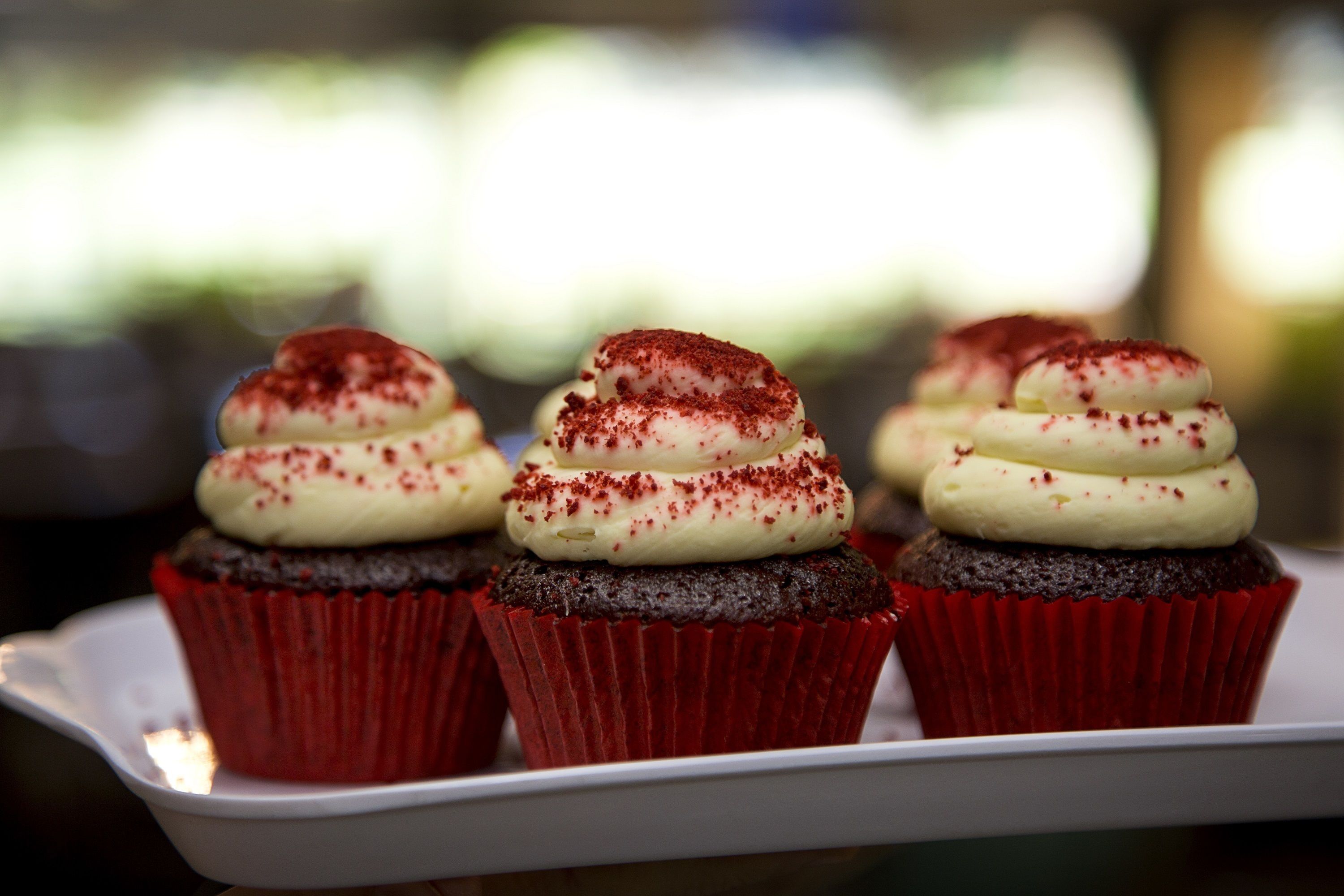 A tray of cupcakes with white frosting and red sprinkles.