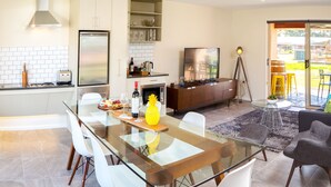 A modern kitchen with a dining area, a TV, and a view of the outdoors.