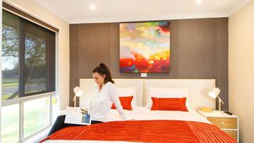 A hotel room with a large bed, two bedside tables, and a window with a view of the outdoors.