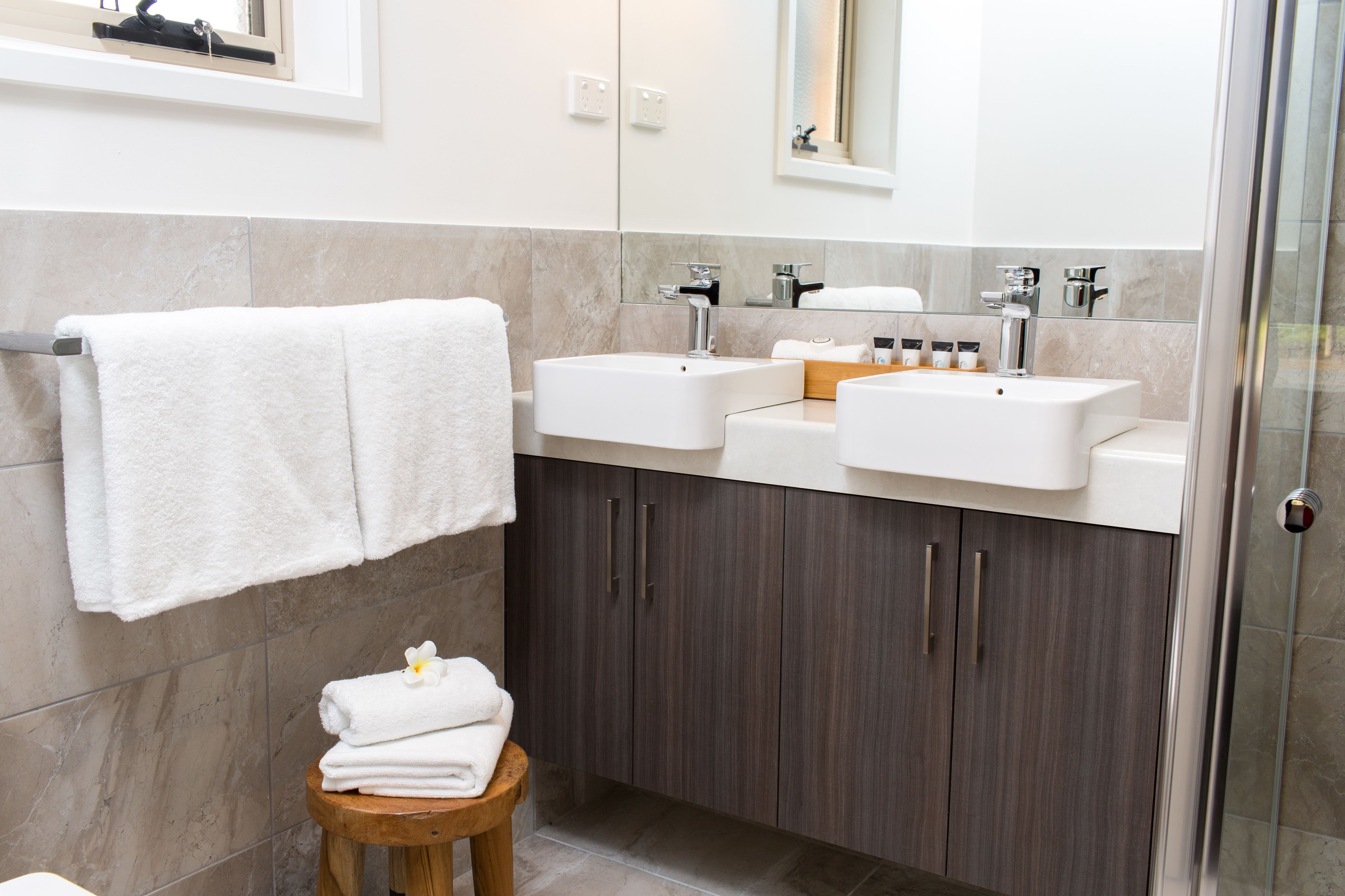 Een moderne badkamer met twee wastafels, een spiegel en een douche.