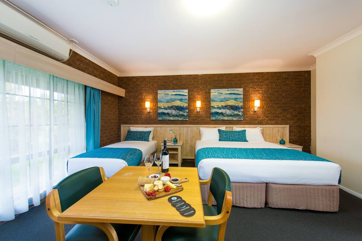Ein Hotelzimmer mit zwei Betten, einem Holztisch mit Snacks und Blick ins Freie.