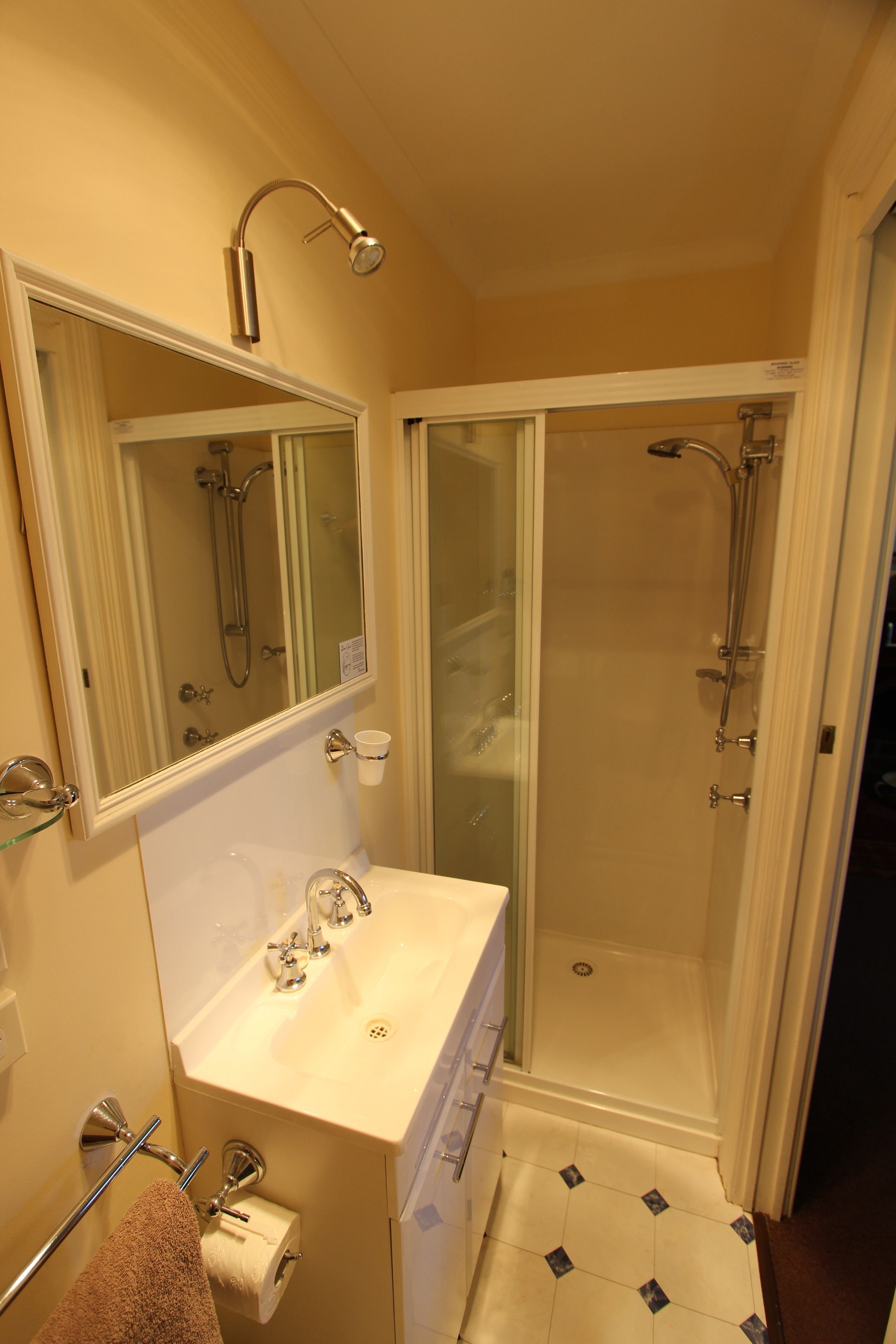 A bathroom with a sink, mirror, towel rack, and a glass-enclosed shower area.