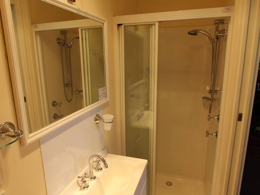 A bathroom with a sink, mirror, towel rack, and a glass-enclosed shower area.