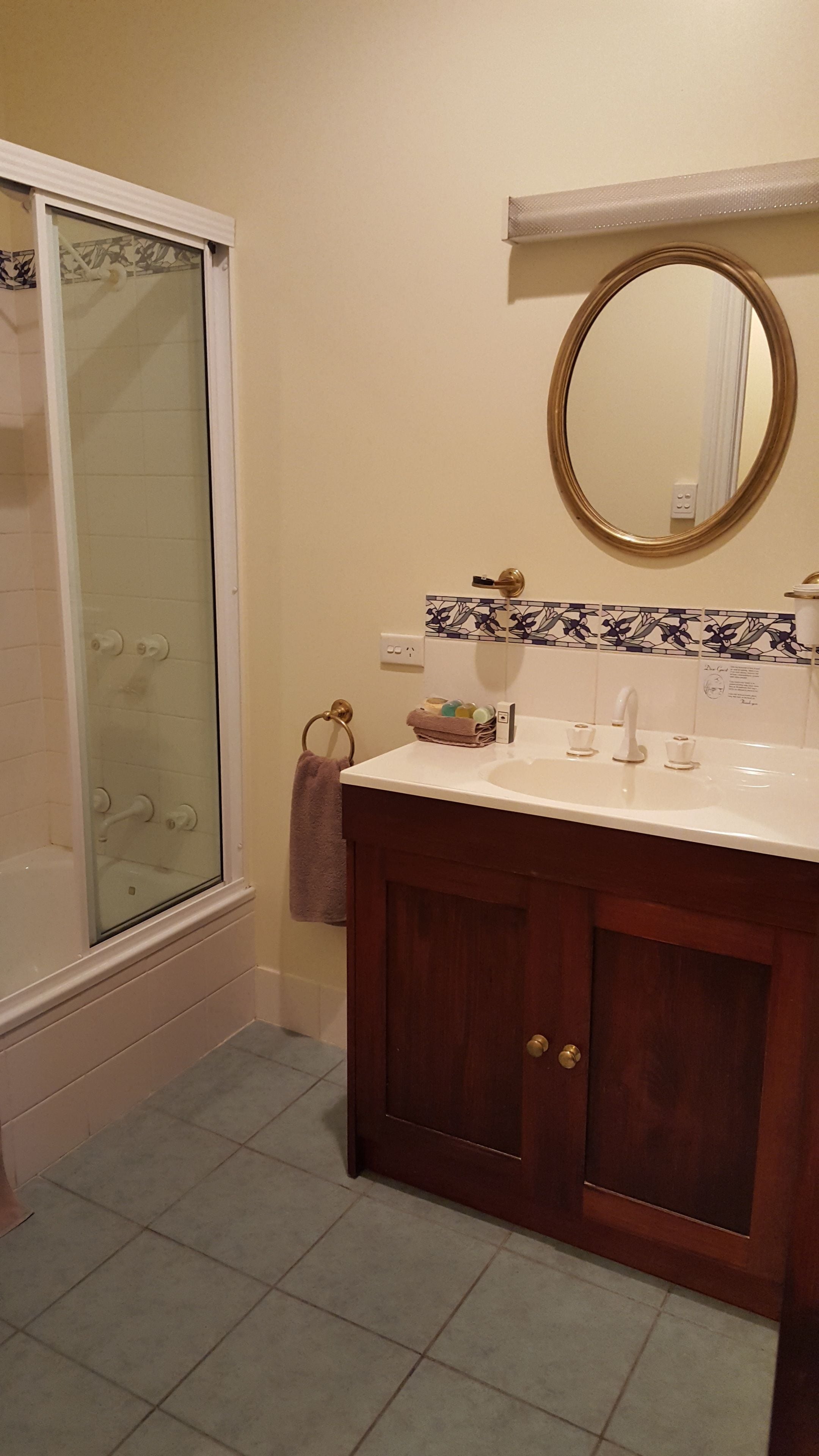 Un baño con cabina de ducha de vidrio, tocador con espejo y piso de baldosas.