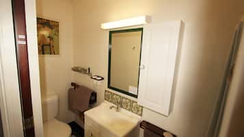 A bathroom with a toilet, sink, mirror, and towel rack.