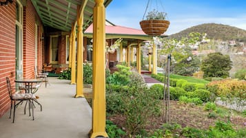 A covered outdoor area with a brick building, yellow pillars, and a garden with various plants and flowers.