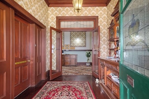 Un pasillo con puertas de madera, una recepción y una alfombra estampada.