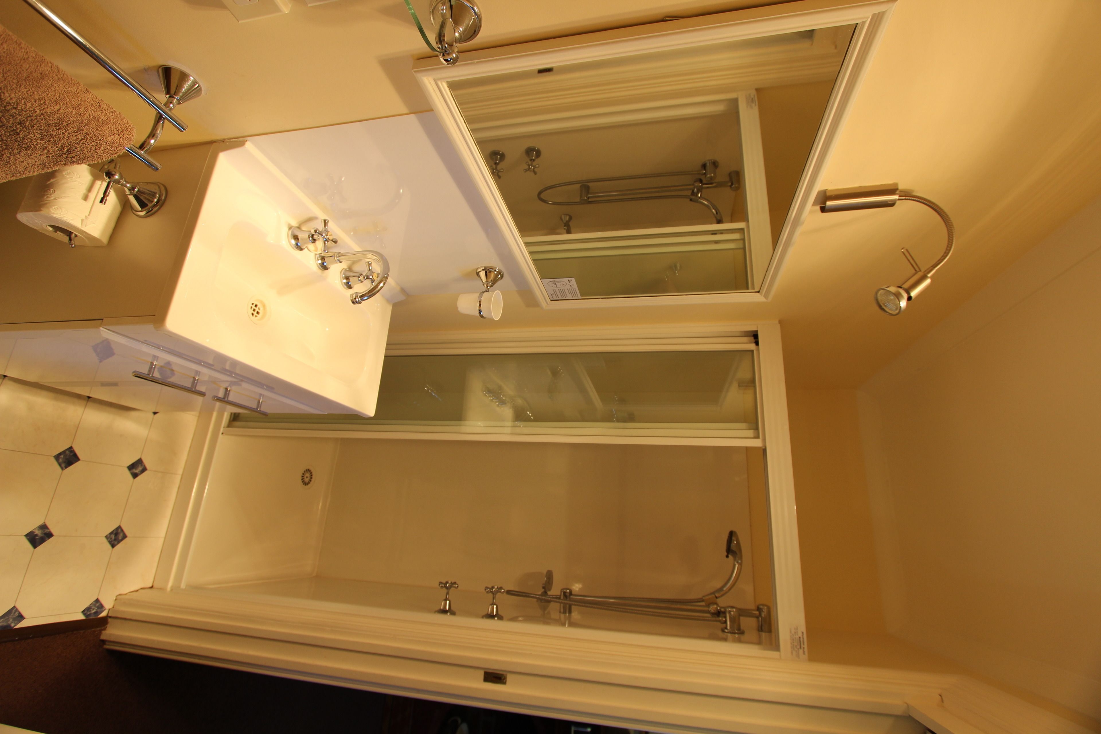 A bathroom with a large mirror, a bathtub, and a sink.