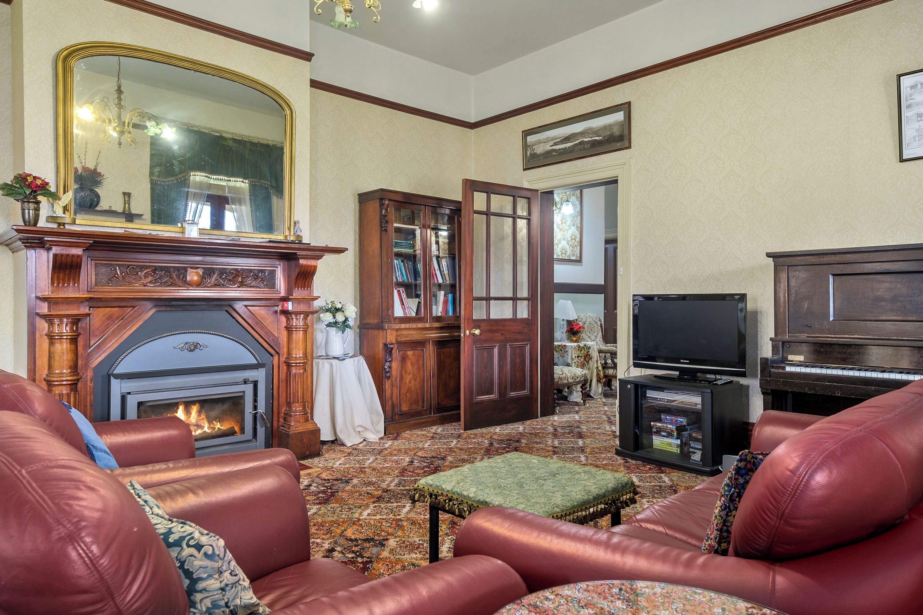 Una sala de estar tradicional con chimenea, sofás de cuero, televisor y piano.