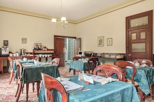 Comedor con mesas dispuestas para una comida, un rincón de café y un letrero con el nombre del salón.