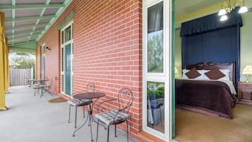 A room with a bed, a window, and a patio area with a table and chairs.