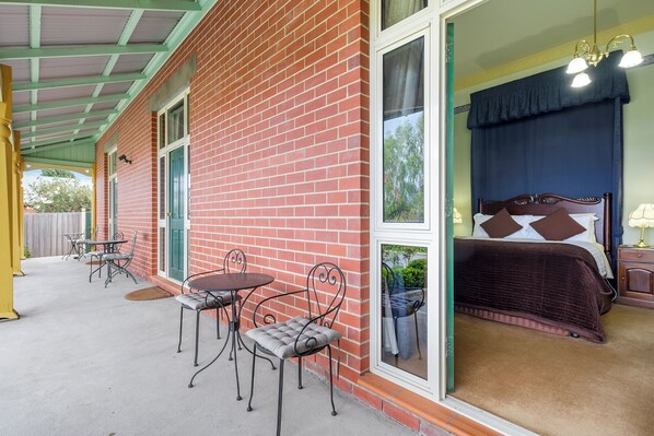 Una habitación con cama, ventana y un patio con mesa y sillas.