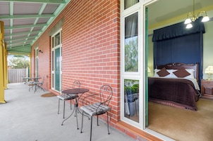 Una stanza con un letto, una finestra e un'area patio con tavolo e sedie.