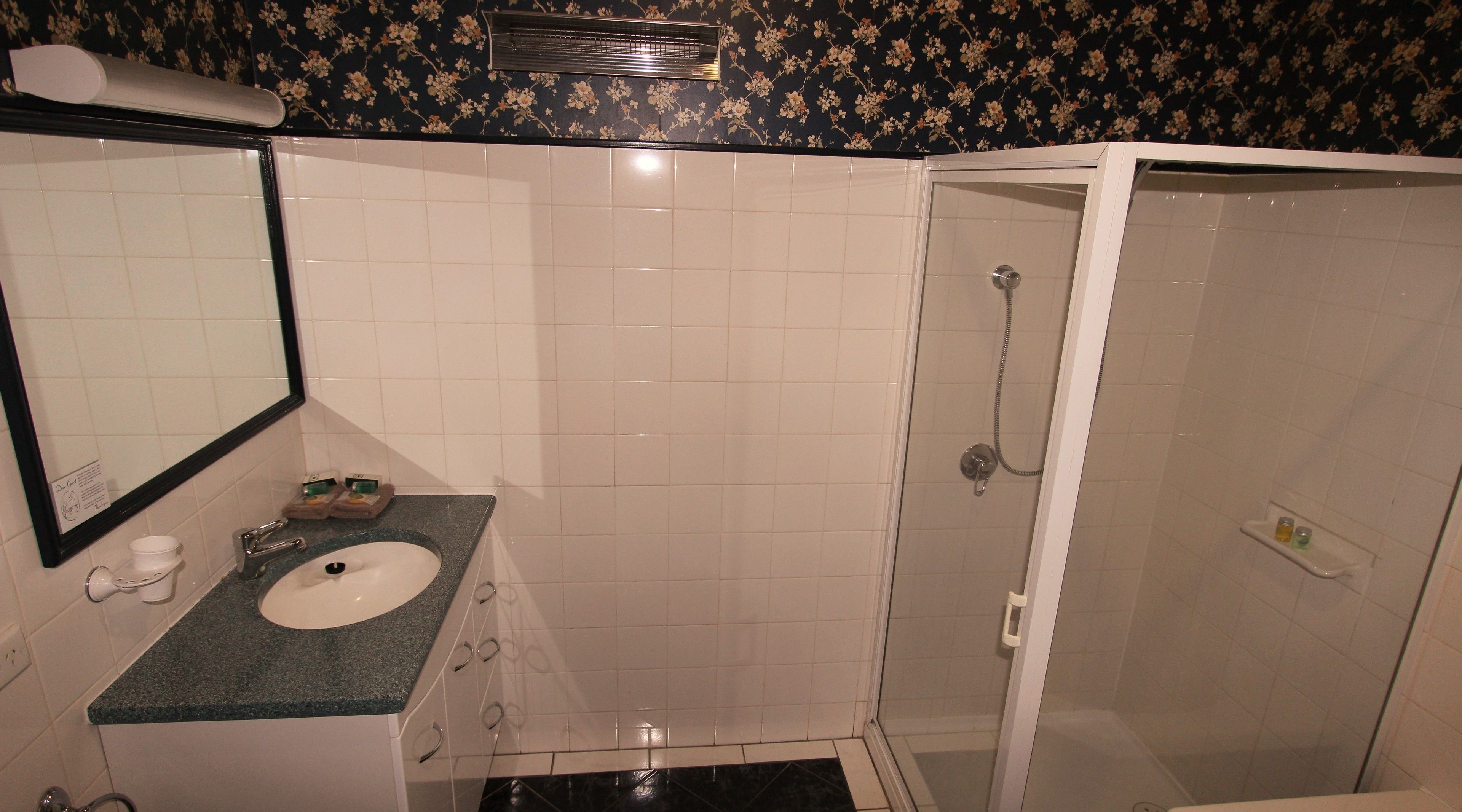 Een badkamer met wastafel, spiegel en douche.