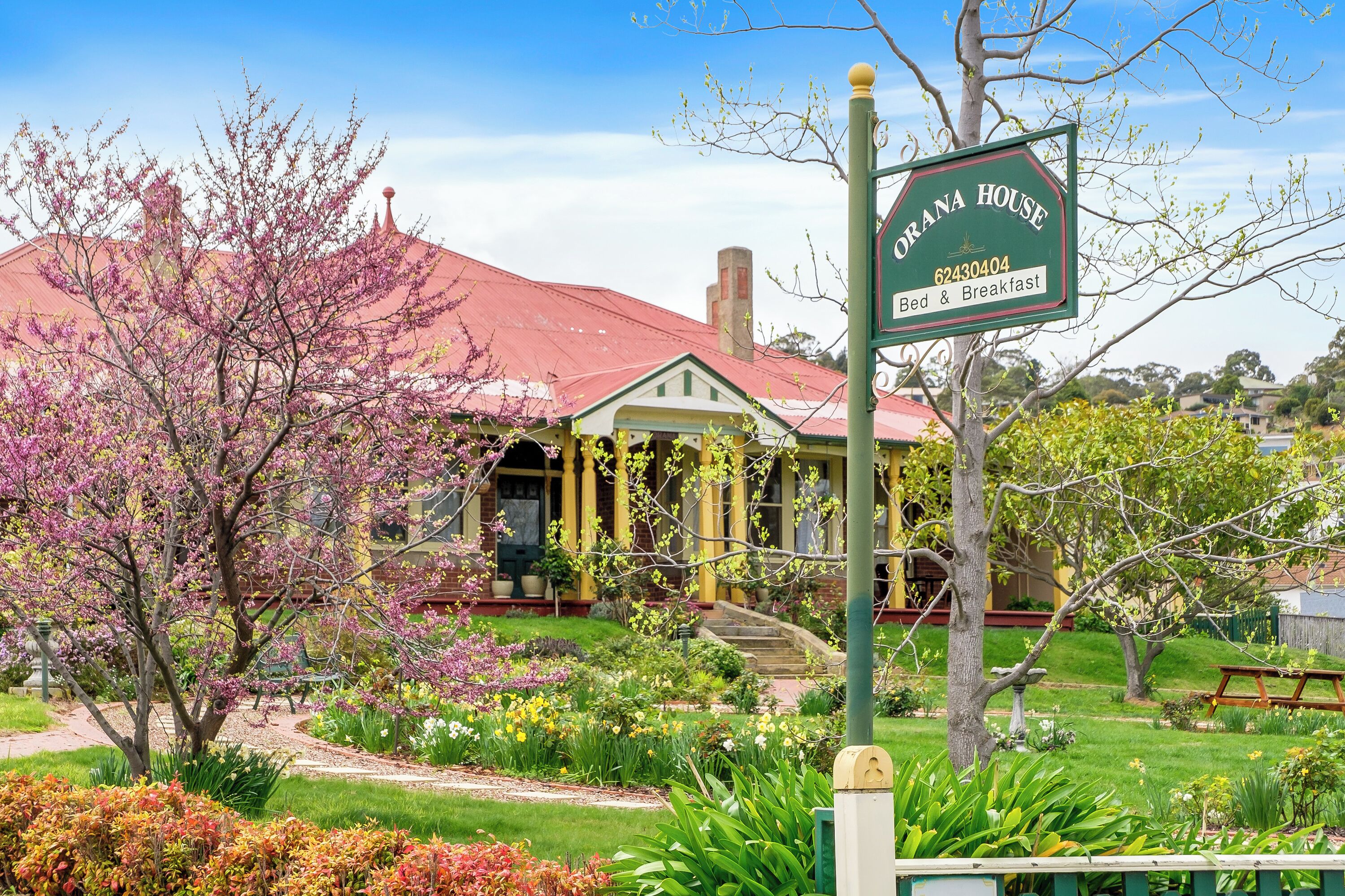 A traditional house with a red roof, a porch, and a sign indicating it is a bed and breakfast.