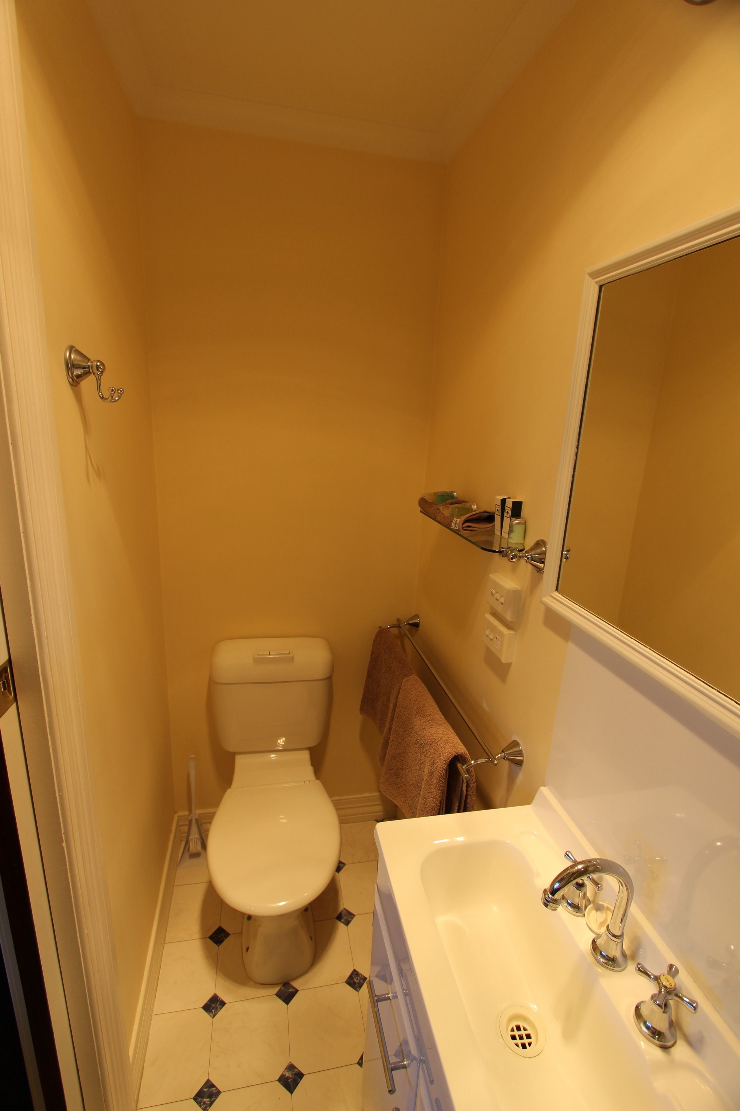 A small bathroom with a toilet, sink, and mirror.