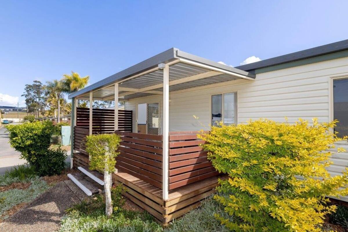 A modern house with a covered porch, a small garden, and a clear sky.