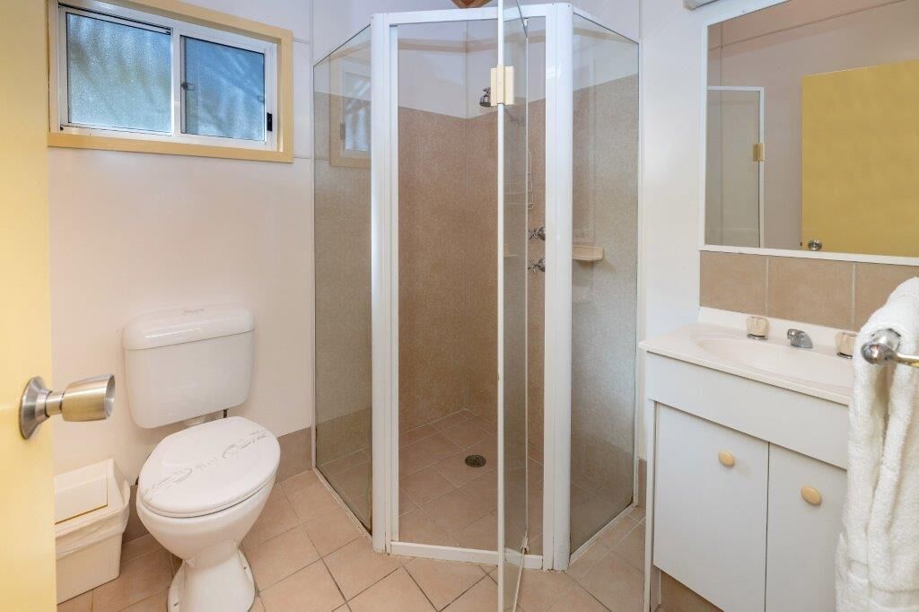 A bathroom with a toilet, a glass-enclosed shower, a sink, and a mirror.
