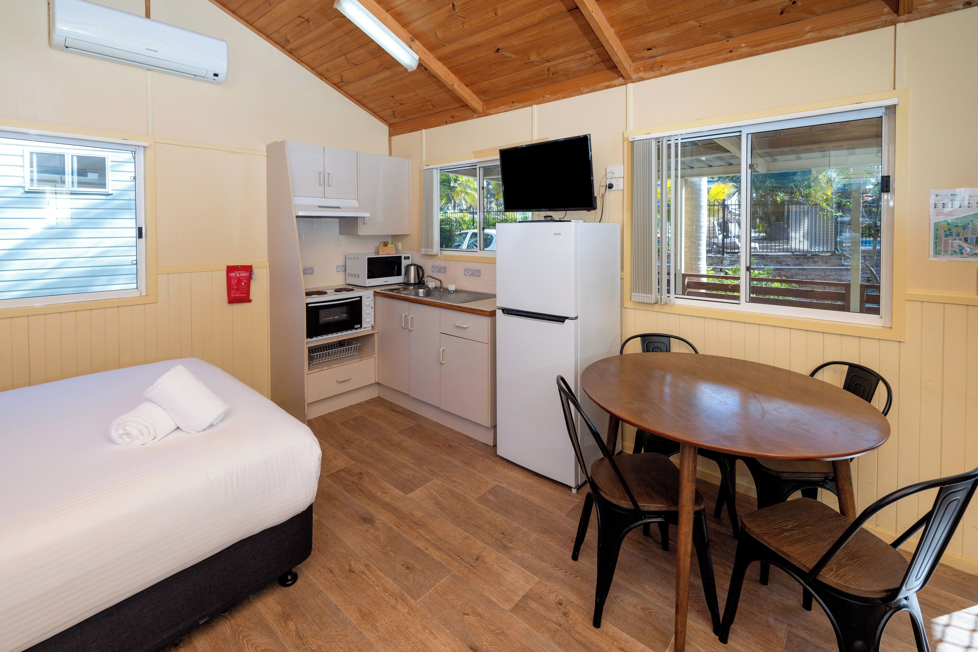 A compact room with a bed, kitchenette, and a dining area.