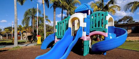 A playground with two slides and a climbing structure.