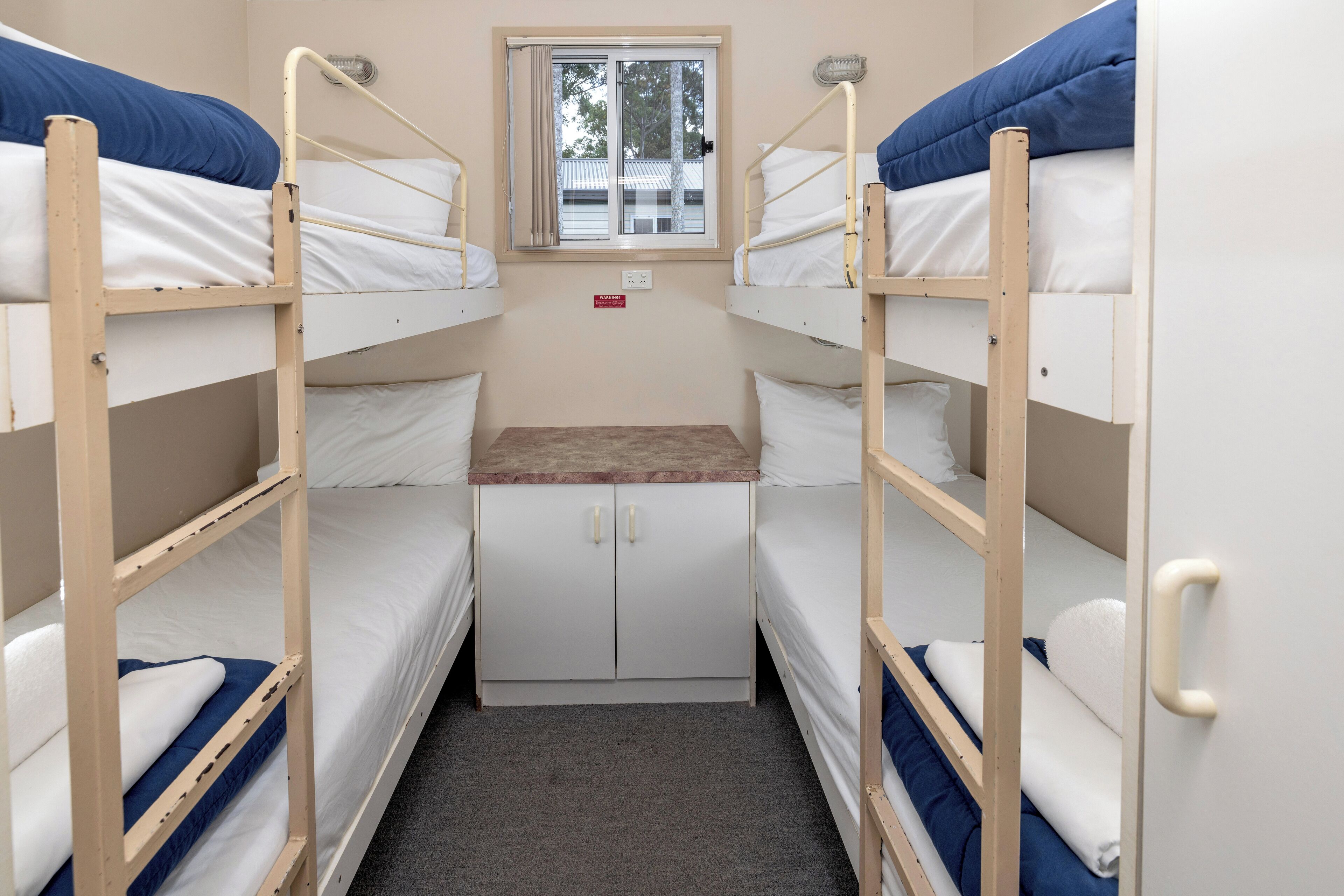 A bunk room with two beds, a small window, and a desk with a chair.