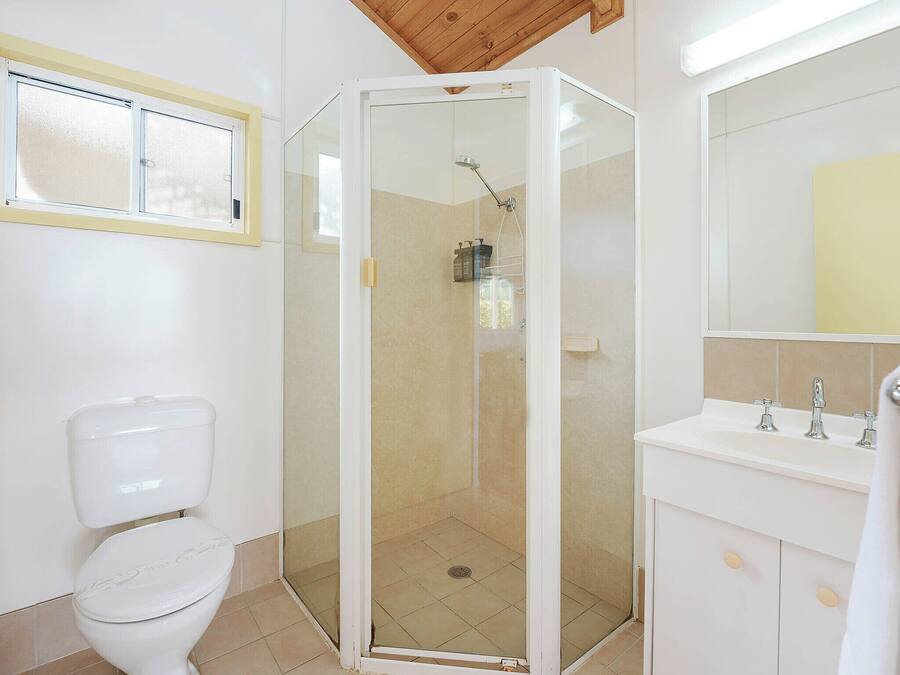 Ein Badezimmer mit Toilette, einer Duschkabine und einem Waschbecken mit Spiegel darüber.