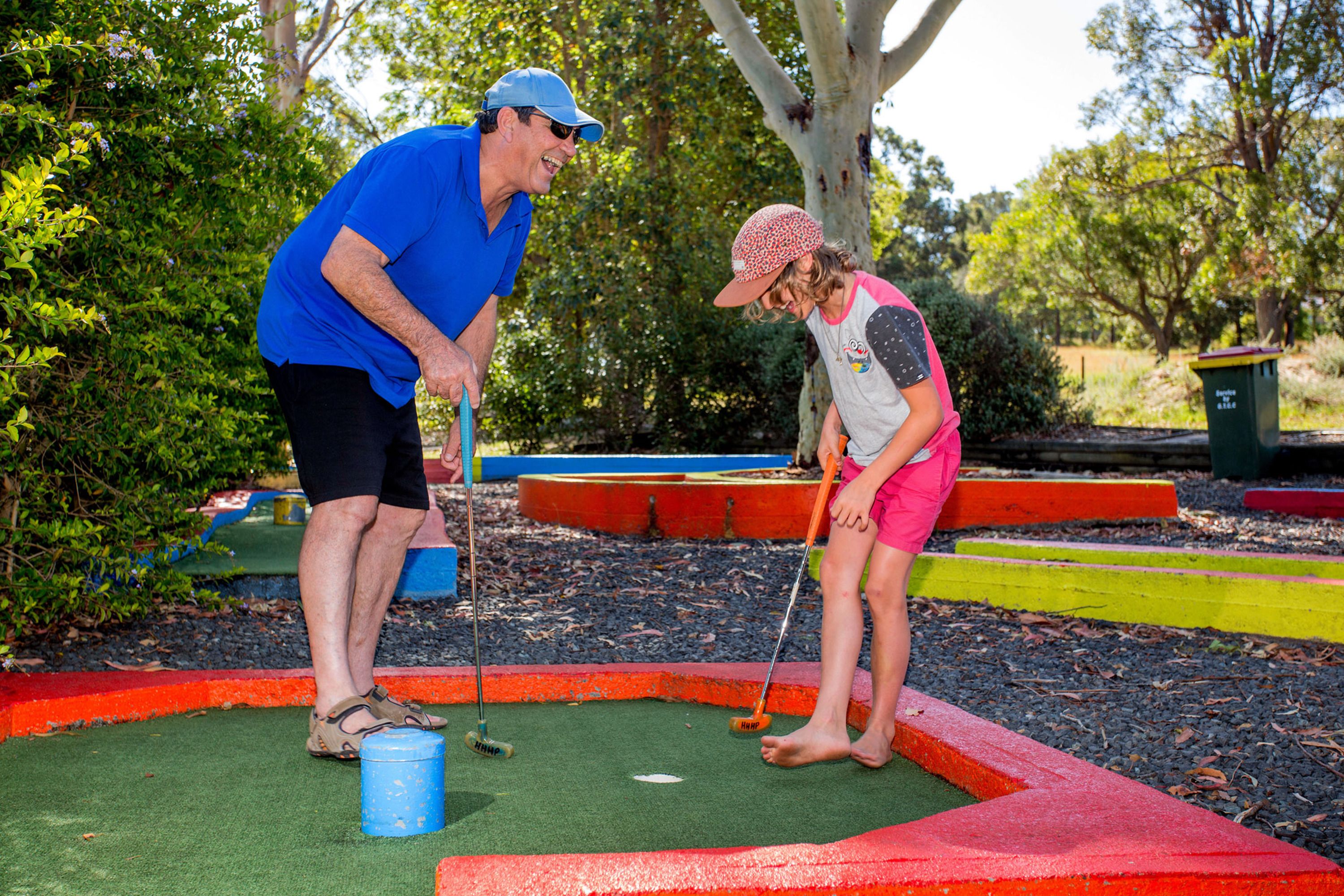 Un campo da mini golf con superficie verde per le putt, un secchio blu e una bordura rossa e gialla.