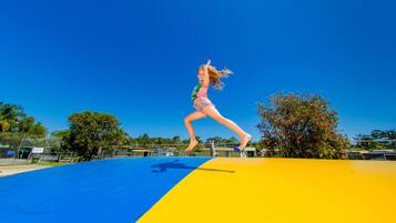 Una persona saltando en un trampolín azul y amarillo.