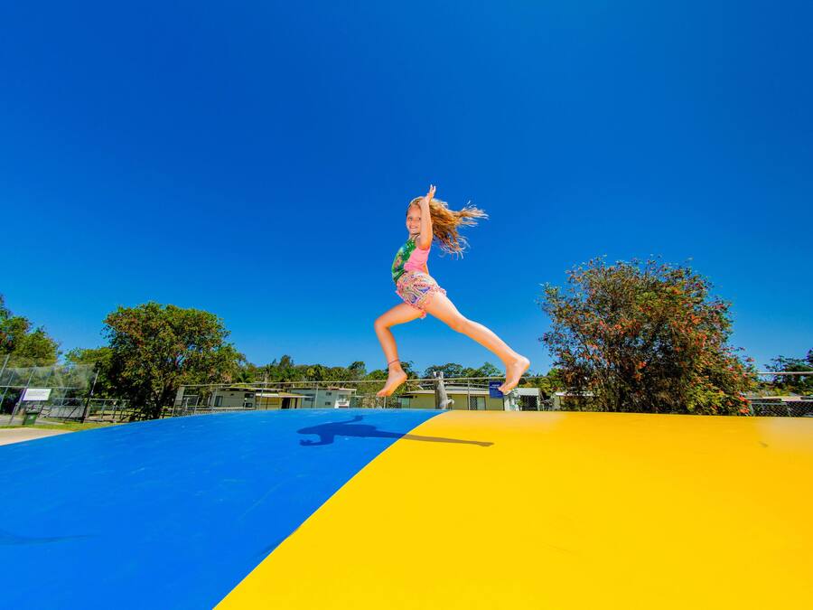 Una persona saltando en un trampolín azul y amarillo.