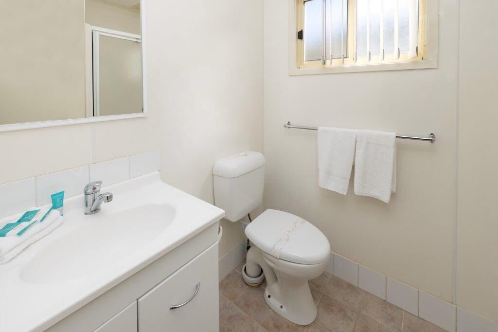 A bathroom with a white sink, a toilet, and a towel rack.