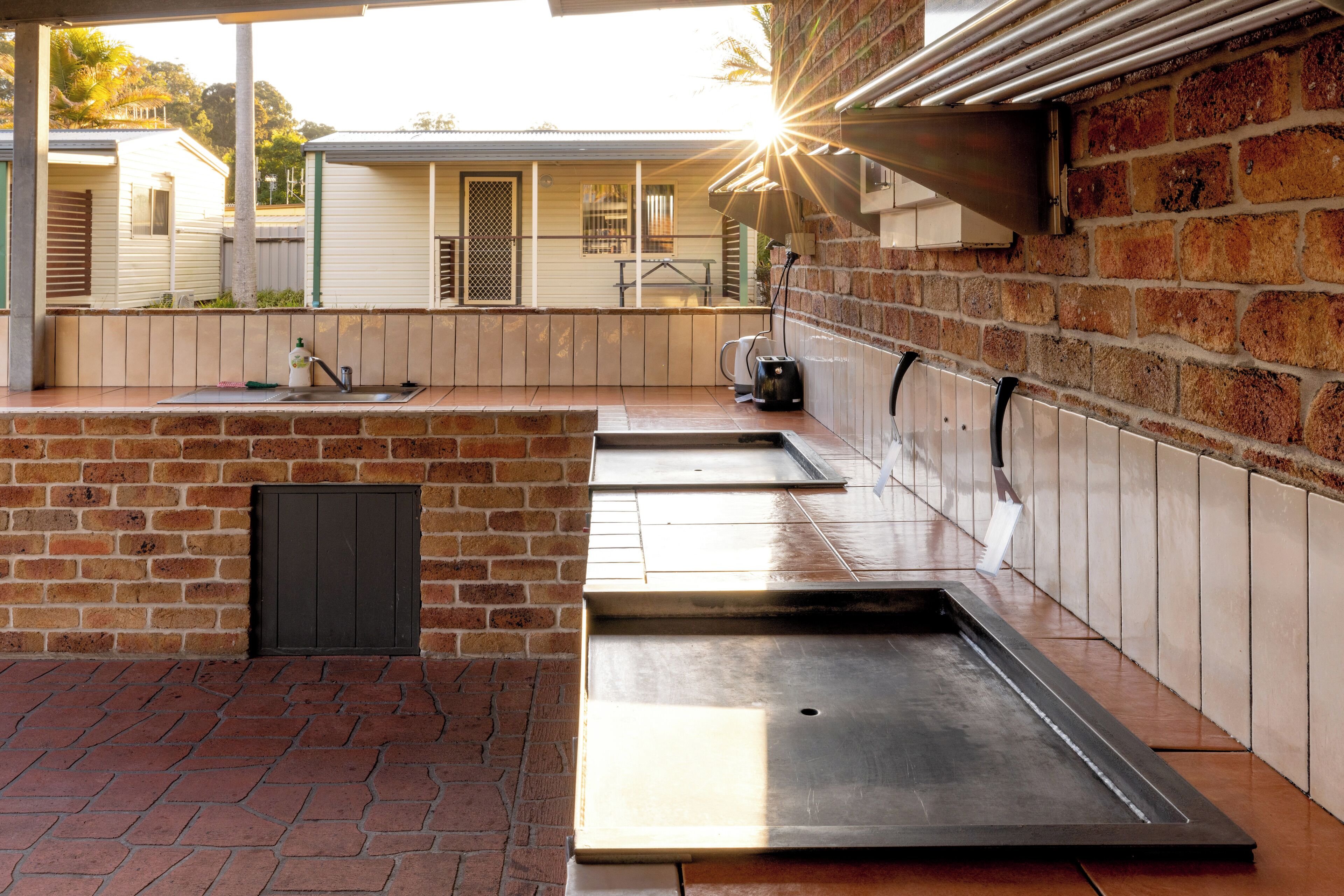 A patio area with a brick wall, metal planters, and a water fountain.