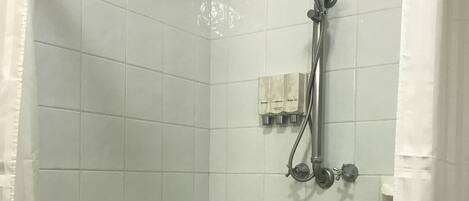 A shower with a bench, a handheld showerhead, and a wall-mounted faucet.