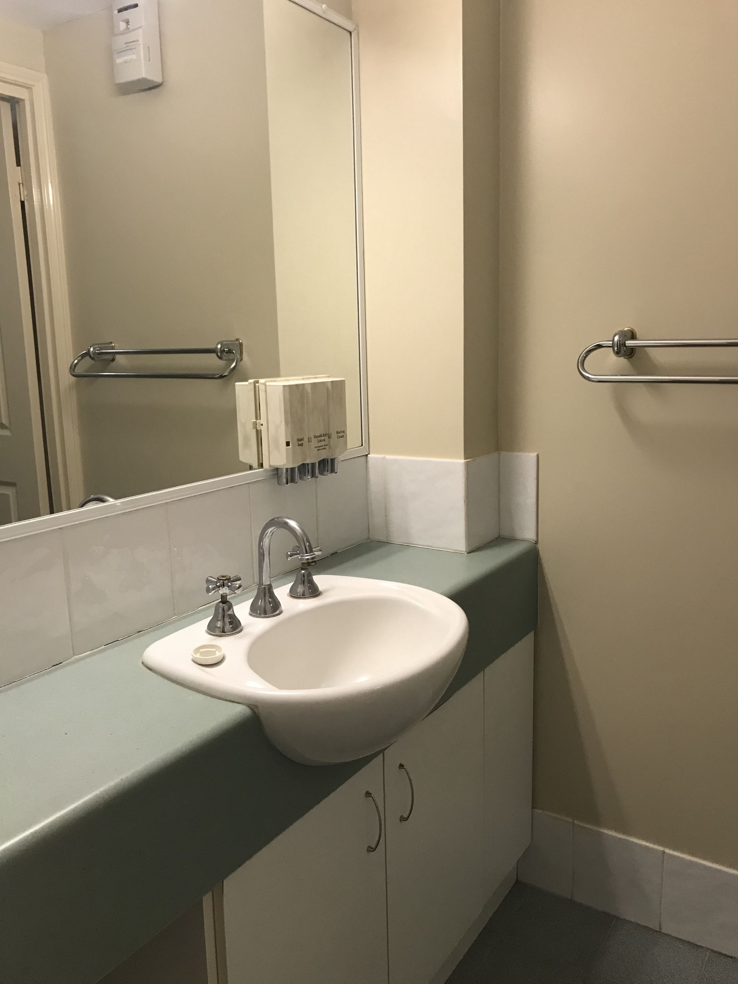 Casa de banho com lavatório branco, espelho e porta-toalhas.