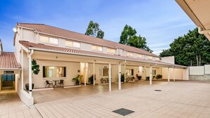 A hotel with a covered outdoor area, multiple rooms, and a tiled floor. - Villa Nova (South Toowoomba)