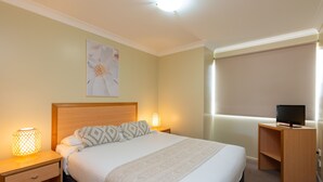 A hotel room with a bed, bedside lamps, a desk with a computer, and a large window. - Villa Nova (South Toowoomba)