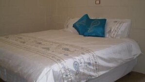 Ein Bett mit einem gemusterten Überwurf und einem einzelnen blauen Kissen.