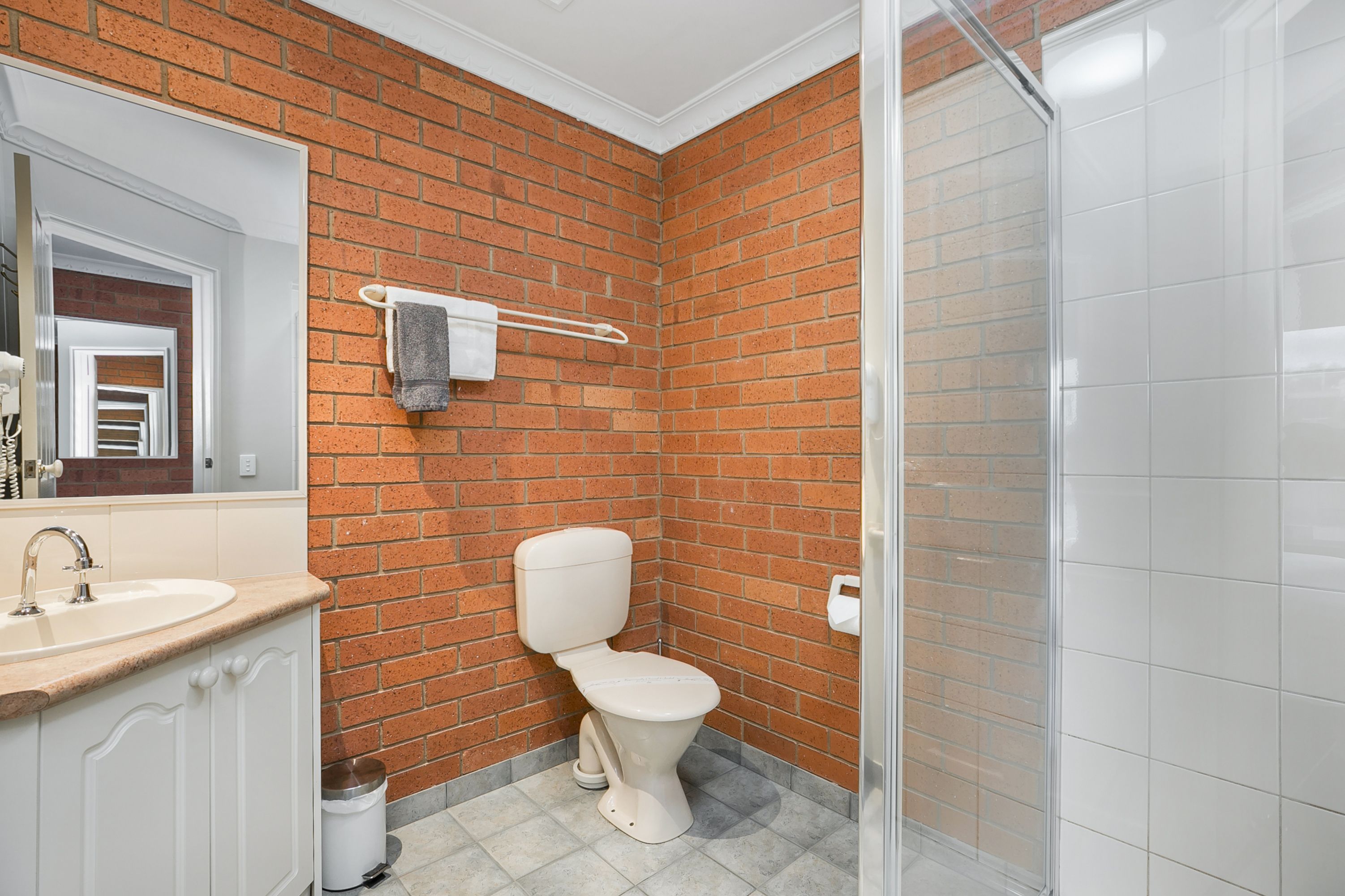 Un baño con un lavamanos blanco, inodoro y zona de ducha.