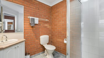 Un baño con un lavamanos blanco, inodoro y zona de ducha.
