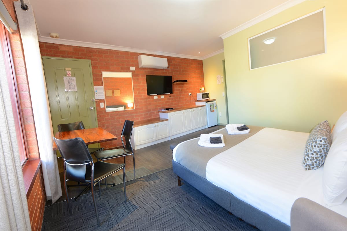Habitación de hotel con cama, escritorio, silla, televisor y microondas.