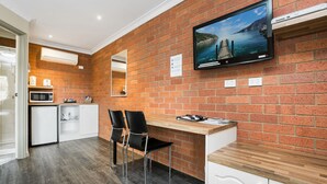Una cocina moderna con pared de ladrillo, televisor de pantalla plana y encimera de madera.
