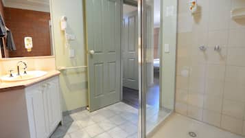 A bathroom with a sink, a hairdryer, and a shower.