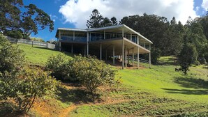 A large, open building with a covered outdoor area, surrounded by a grassy landscape and a small pond. - Ingleside Stud Farm (Tallebudgera Valley)