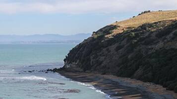 A coastal landscape with a beach, rocky cliffs, and a view of the sea.
