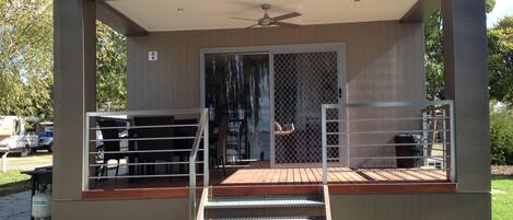 A modern building with a covered patio area, a staircase leading to a deck, and a fenced outdoor seating area.