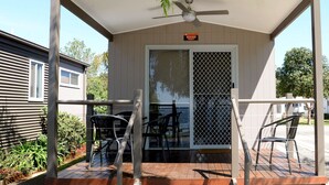 A covered outdoor area with a table and chairs, a ceiling fan, and a view of a house in the background. - Ski Club Holiday Park (Mulwala)