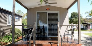 A covered outdoor area with a table and chairs, a ceiling fan, and a view of a house in the background. - Ski Club Holiday Park (Mulwala)