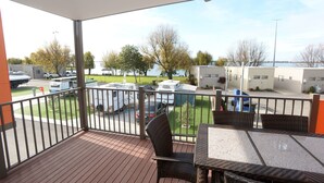 A balcony with a view of a parking area, outdoor furniture, and a building in the background. - Ski Club Holiday Park (Mulwala)