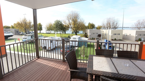 A balcony with a view of a parking area, outdoor furniture, and a building in the background. - Ski Club Holiday Park (Mulwala)