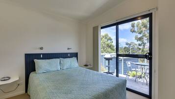 A bedroom with a bed, a nightstand, a window, and a view of an outdoor patio.